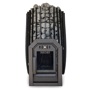 A front, straight-on view of a barrel-shaped black metal sauna stove against a white background. The stove features a tall outer cage of vertical metal slats tightly packed with rounded grey stones. At the bottom center, the dark grey firebox door features a square glass window with the embossed word 'COZY' on top. Framing the entire door assembly is a matching, chamfered black metal trim collar. The window is dark and unlit, showing an empty firebox interior.