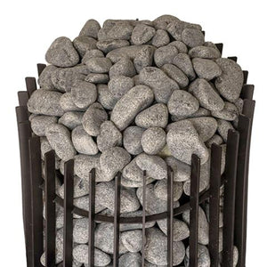 A high-angle, close-up shot focusing on the top section of a black metal sauna stove against a white background. The frame consists of thick, vertical rectangular metal slats arranged in a circular cage formation. Inside, the stove is packed tightly with a dense mound of rounded, textured grey stones that pile significantly over the top rim of the metal cage structure.