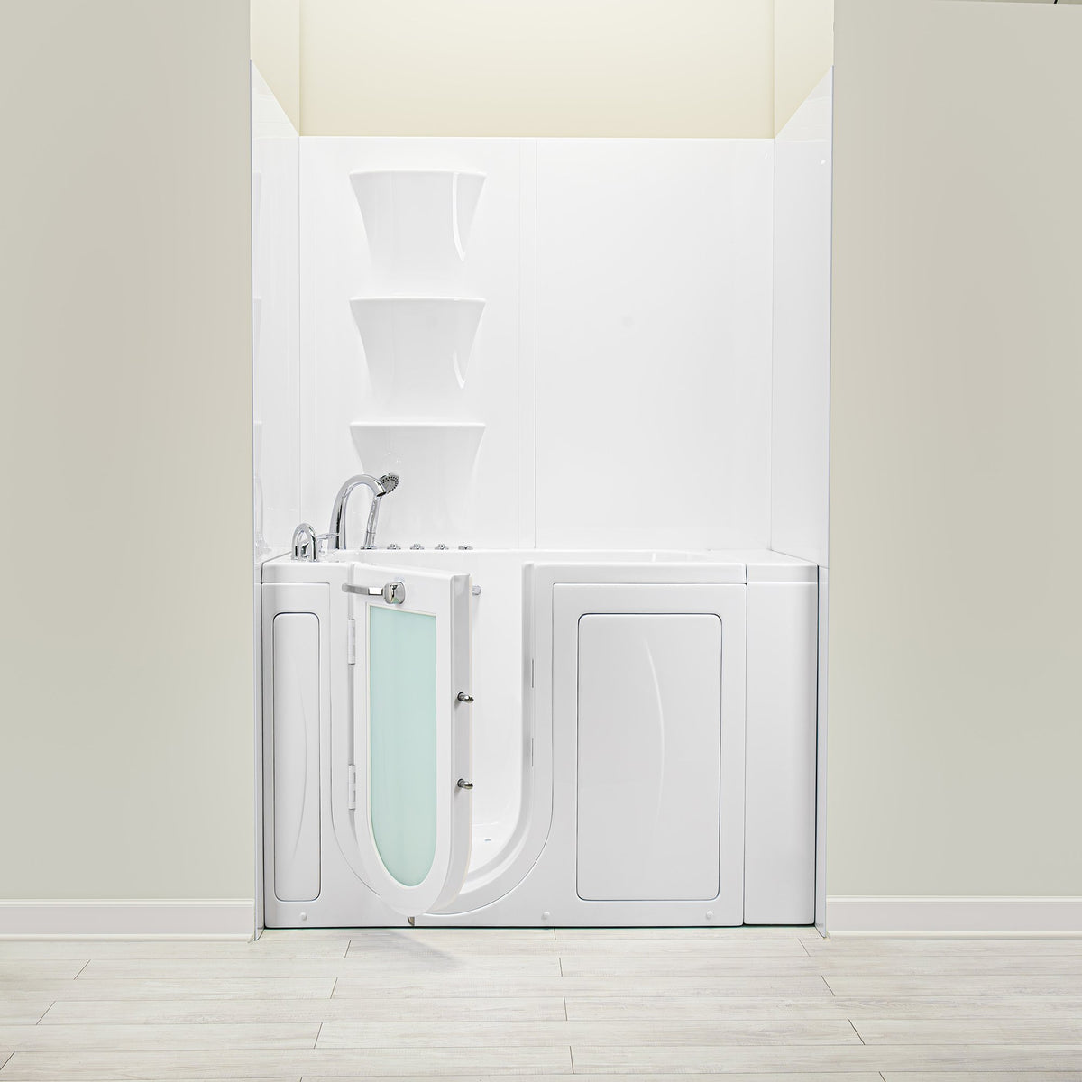 White walk-in bathtub with an open outward-swinging door featuring a frosted glass window. The tub is installed against a solid white wall surround with three integrated corner shelves. Chrome fixtures, including a high-arc faucet and handheld shower head, are mounted on the left deck. The unit is shown in a room setting with light-colored flooring and neutral walls.