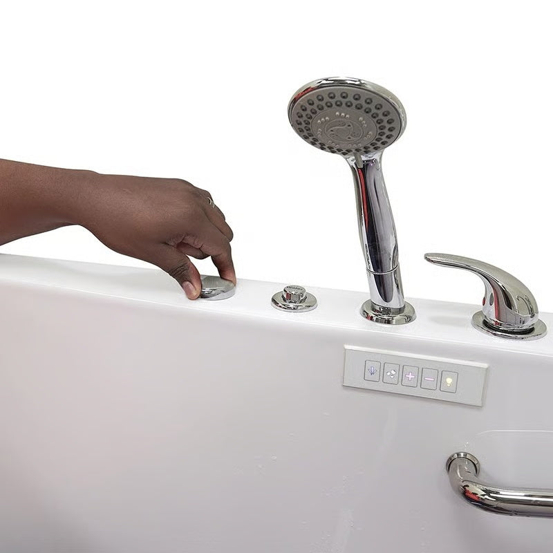 Close-up of a hand adjusting a control dial on the rim of a white walk-in bathtub, with chrome handheld shower, faucet handle, control panel, and grab bar visible.
