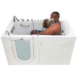 White walk-in bathtub with a man seated inside using the handheld shower, closed entry door, grab bar, hydrotherapy jets, and chrome faucet, viewed from the side.