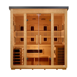 A straight-on front view of a wide, light-tan wooden sauna cabin with a dark gray roof. The glass facade includes two fixed outer windows and central double doors with vertical wooden handles. Inside, a two-tier bench wraps around the walls. Dark infrared panels with glowing red center lines are built into the interior: four spaced across the back wall behind a slatted backrest, three on each side wall, and a horizontal panel below the bench. A wooden heater cage is on the bottom left.