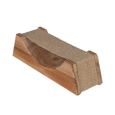 A wooden sauna headrest with a wide base that tapers up slightly toward a flat top surface, isolated on a white background. A piece of tightly woven, coarse beige fabric stretches across the top to act as a flexible neck support. The side panel is made of smooth, medium-brown wood with distinct circular grain patterns. A large, smooth U-shaped curve is carved into the top edge of this wooden panel, allowing the fabric above it to cradle downward.