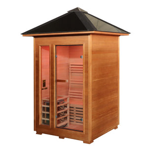 The SunRay Bristow 2-Person Outdoor Wet/Dry Traditional Sauna with 4.5kW Harvia Heater (HL200D2) features a compact wooden construction with a distinct pyramid-style pitched roof and overhang. The front facade includes a glass entry door next to a vertical side window, providing a clear view of the interior wooden benches, slatted backrests, and lighting fixtures.