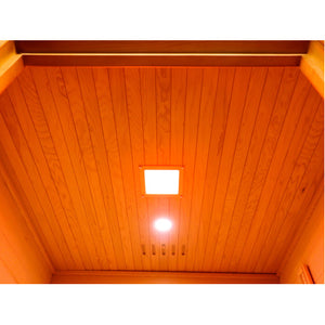 The interior ceiling of the sauna features vertical wood paneling equipped with a square ceiling light fixture, a recessed circular spotlight, and a ventilation grate.