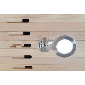 A close-up shot of a round metal temperature sensor plate with a hook and an adjacent circular vent or light fixture, mounted on a light-colored horizontal wood-paneled sauna wall.