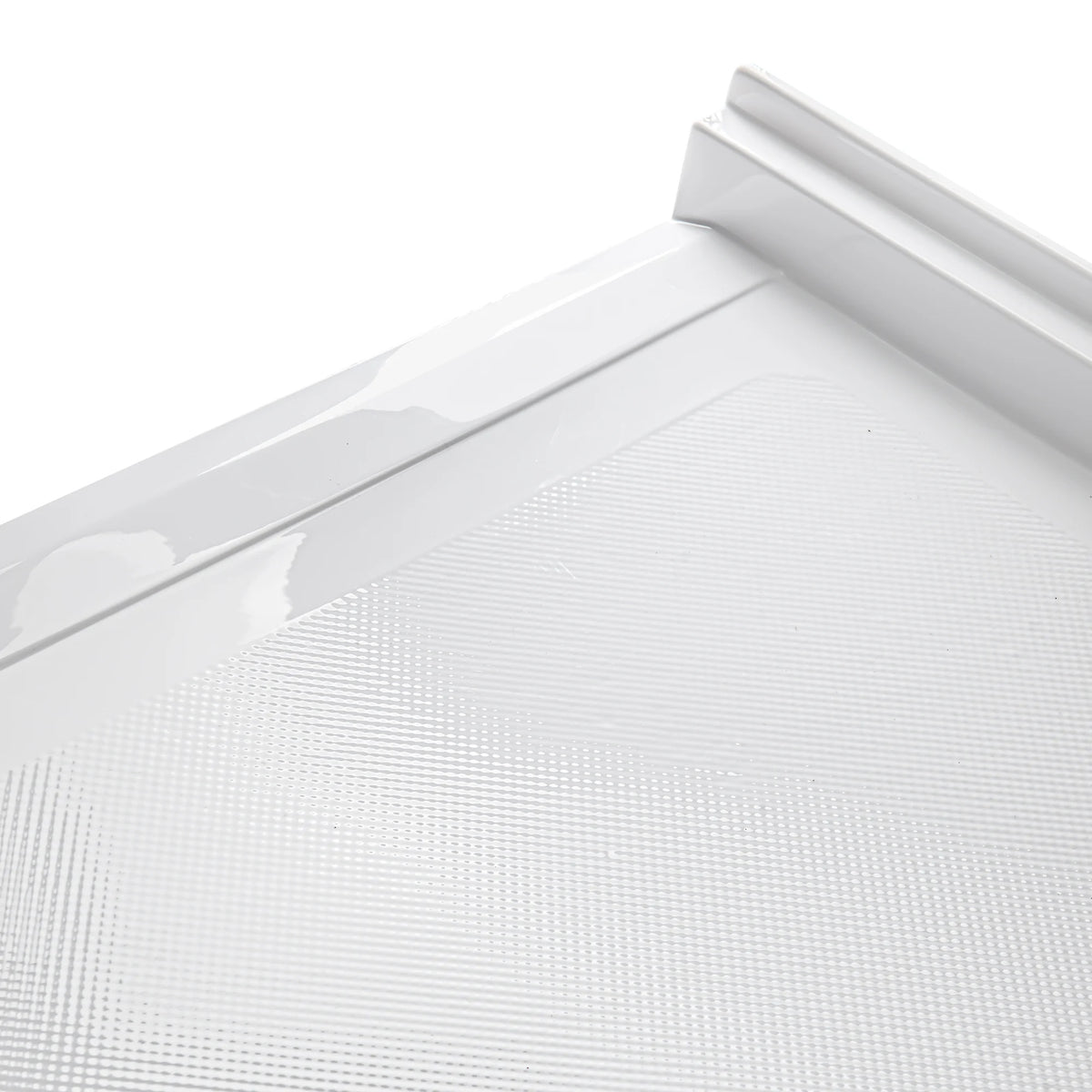 A close-up, angled view of the corner of a white acrylic shower base. The image highlights a detailed, slip-resistant textured pattern on the floor surface consisting of small, raised dots. It also shows the smooth, glossy finish of the integrated tiling flange and the raised outer edge of the base.