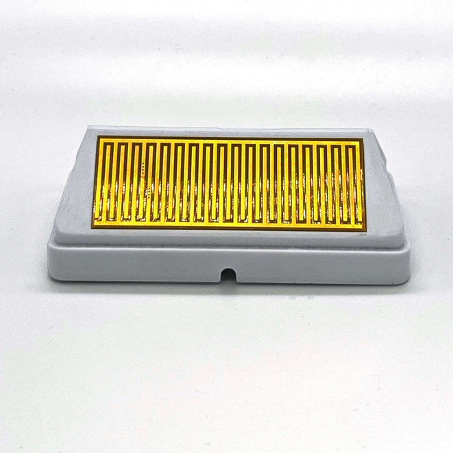A grey rectangular sensor module sits horizontally against a white background, featuring a prominent gold-colored zigzagging grid pattern centered on its top surface.