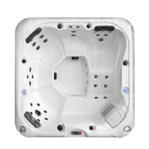 A top-down view of a square white acrylic hot tub against a plain white background. The interior features molded seating for five to six people, including three dark gray headrests, multiple integrated chrome massage jets, a textured footwell with an embossed "Canadian Spa Co." logo, and a digital control panel on the bottom rim.