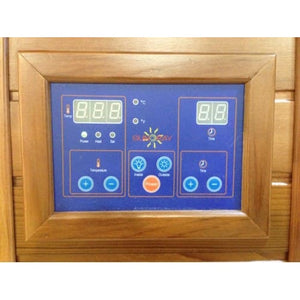 A close-up shot of a digital control panel mounted on a wooden sauna wall, featuring blue display screens with green digital numbers, status indicator lights, the SunRay logo, and touch-sensitive buttons for adjusting temperature and time.