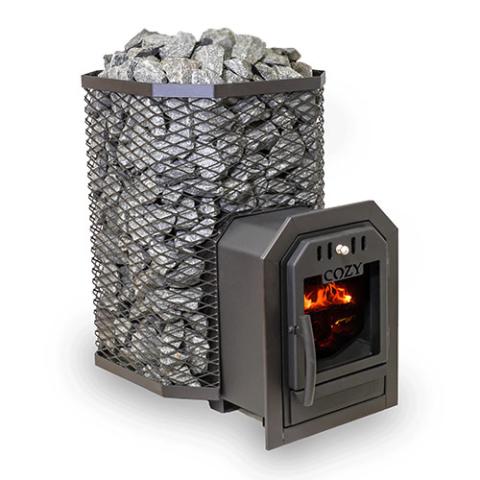 A Cozy Heat Thru-Wall wood-burning sauna stove is shown from an angled perspective against a plain white background. The unit features a tall, octagonal black wire mesh cage packed to the top with grey sauna stones. Extending forward to the right is the structural firebox tunnel designed for through-wall installation, ending with a closed black cast-iron door. Bright orange flames are visible actively burning inside the glass window beneath the embossed "COZY" brand name.