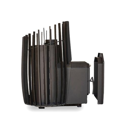 A side profile view of an empty black metal thru-wall sauna stove against a white background. On the left, the barrel-shaped body is shown without rocks, revealing the solid internal core wrapped in an outer cage of vertical rectangular slats that taper upward in height. Extending horizontally to the right is a box-shaped firebox tunnel, complete with its front door panel assembly and a matching unattached metal trim collar spaced just behind it.