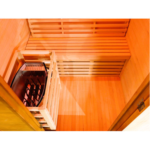 The image displays the interior of the sauna, featuring a Harvia heater enclosed in a protective wooden guard, a wooden bench with a slatted backrest, and warm wood flooring.