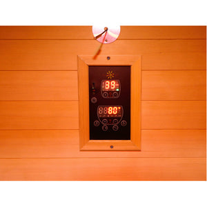 The image displays a digital control panel mounted on the warm wooden wall paneling of the sauna, featuring dual digital displays with red LED indicators and multiple function buttons.