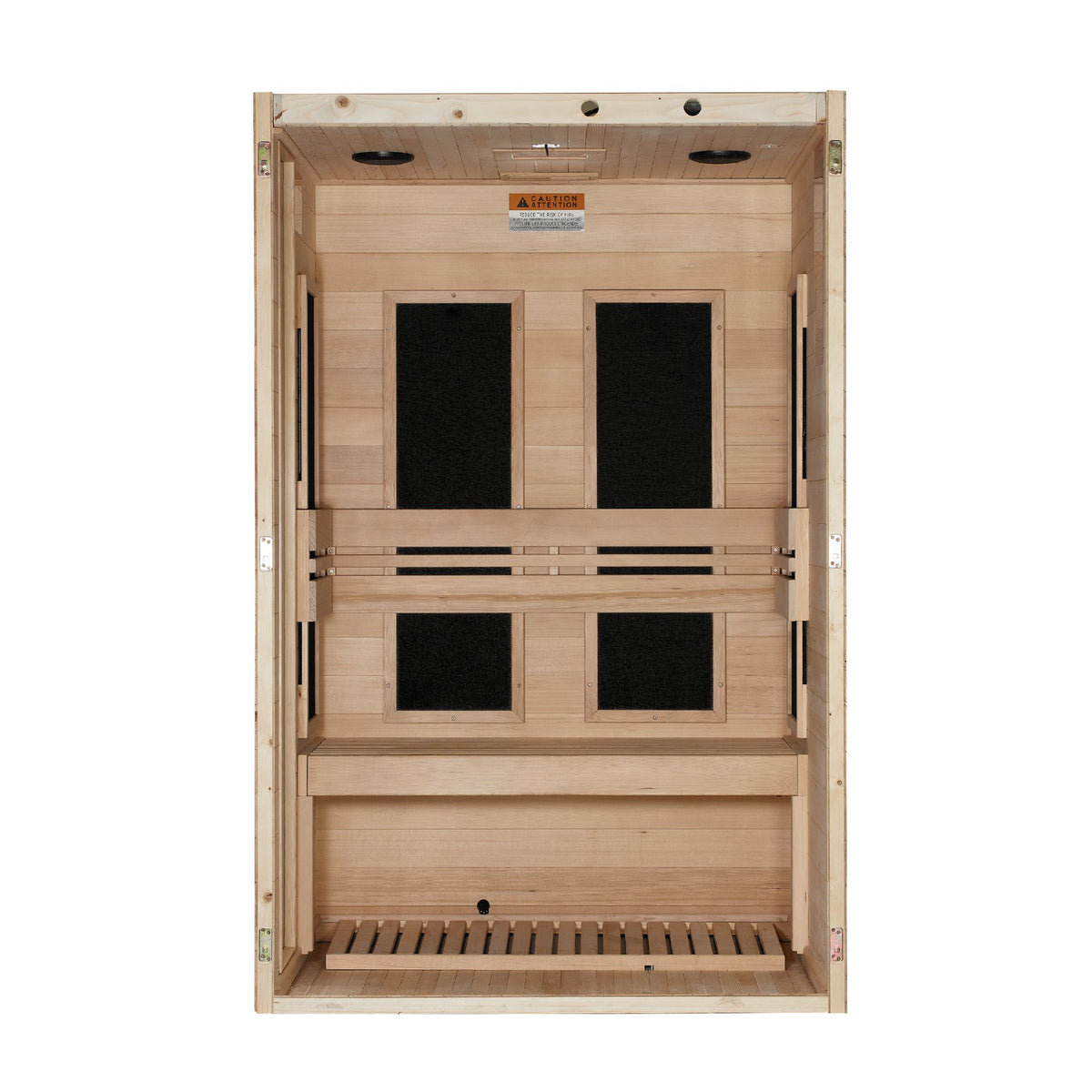 A straight-on view looking directly into the open front of a light-colored wood infrared sauna cabin. The interior back wall features four large, vertical rectangular black heating panels arranged in pairs (two upper, two lower), partially divided by horizontal wooden backrest slats. A wide wooden bench spans the width of the lower section, below which is a matching light wood slatted floor mat. The top ceiling panel has small circular cutouts, and a warning label is affixed above the panels.