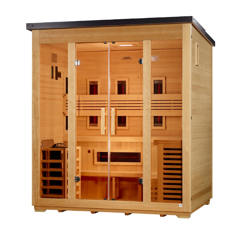 A wide, light-tan wooden sauna cabin with a dark sloped roof, viewed from a slight right angle. The front facade features two outer windows and central double glass doors with vertical wooden handles. Inside, an L-shaped two-tier bench wraps the walls, paired with slatted backrests. Glowing red-centered dark infrared panels line the interior: three on the back wall, three on each side wall, and one horizontal panel below the back bench. A heater cage sits on the bottom left.