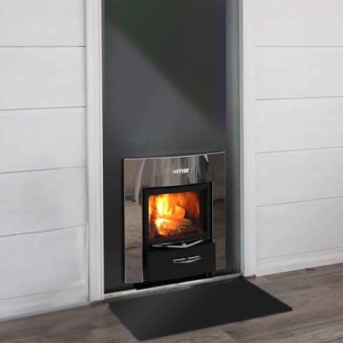 A wood-burning sauna stove is shown from an elevated angle against a white background. It features a polished stainless steel body with a deep, empty top stone compartment surrounded by ventilated trim. Extending forward is a wide stainless steel wall flange with a dark grey header panel and a white "HARVIA" logo. At the bottom, a large rectangular glass firebox door reveals a bright orange fire above a matte black ash drawer.