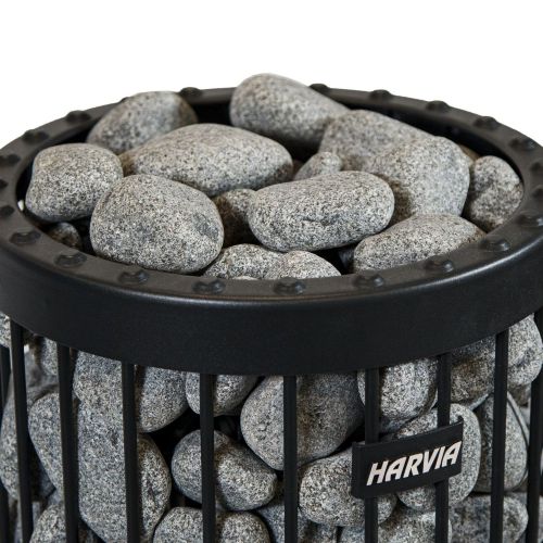 A small cluster of five rounded, oval-shaped olivine sauna stones piled together against a solid white background. The stones are medium grey with a speckled, finely textured granite-like appearance. One prominent, flattened stone rests horizontally across the top of the pile, while the other four are clustered underneath and slightly behind it. Each stone has a smooth, naturally weathered surface with soft, rounded edges, ranging in size from 5 to 10 centimeters.