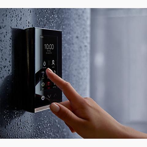 A vertical, rectangular digital control interface with a brushed silver or metallic trim and a glossy black screen. The display shows white text and icons on a dark background. At the top, "102°" is prominently displayed in large white numbers. Below it is a grid of selectable icons including a water droplet for shower, a person for users, a steam cloud, lighting rays, a music note, and a lotus flower. At the bottom, three physical or touch buttons show a power symbol, a blue down arrow, and a red up arrow.