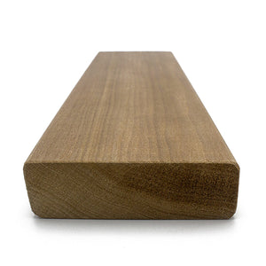 A rectangular wood plank viewed from a low-angle perspective, displaying the cross-section end grain in the foreground and the long face extending backward.