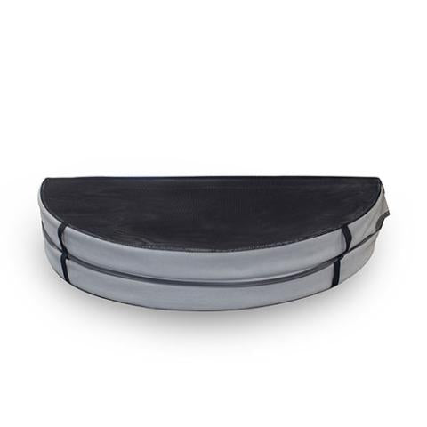 A thick, circular grey hot tub cover sits on a white surface. The cover is upholstered in a smooth, matte vinyl material and features a distinct seam running across its diameter, splitting the top into two symmetrical semi-circles for folding. A short, horizontal fabric handle is stitched onto the lower left side of the overhanging skirt, which runs along the entire outer edge of the cover.