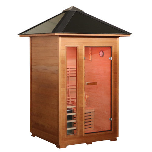 The SunRay Bristow 2-Person Outdoor Wet/Dry Traditional Sauna with 4.5kW Harvia Heater (HL200D2) features a compact wooden construction with a distinct pyramid-style pitched metal roof and overhang. The front facade includes a glass entry door next to a vertical side window, providing a clear view of the interior wooden benches, slatted backrests, and lighting fixtures.