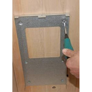 The image shows a hand using a screwdriver to secure a metal mounting bracket onto the wooden interior wall panel of the sauna.
