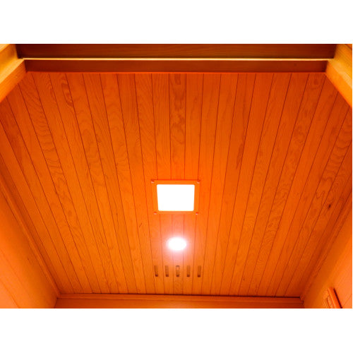 The interior ceiling of the sauna features vertical wood paneling equipped with a square ceiling light fixture, a recessed circular spotlight, and a ventilation grate.