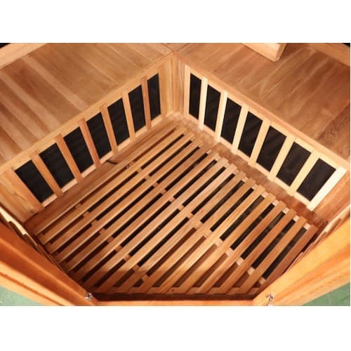 An interior perspective of the SunRay Sauna Bristol Bay Indoor FAR Infrared Corner Sauna (model HL400KC_5), showing the lower corner bench area with slatted wooden floorboards and black infrared heating panels behind wooden safety guards.