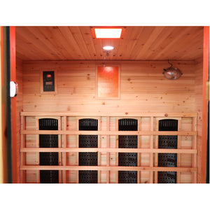 The interior of the sauna features warm wooden wall paneling and flooring, a digital control panel mounted on the left wall, an informational instruction frame centered above the backrest, an air purification system on the upper right wall, a square light fixture and a recessed circular light on the wooden ceiling, and a wide slatted wooden backrest housing four vertical black infrared heating panels.