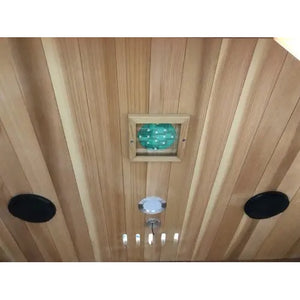 An interior perspective of the SunRay Savannah 3-Person Infrared Cedar Sauna (model HL300K_4), showing the cedar wood ceiling outfitted with two black round speakers, a central recessed light, ventilation slots, and a square chromatherapy lighting panel.