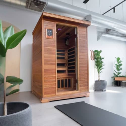 Studio product shot of the SunRay Sierra 2-Person Indoor Infrared Cedar Sauna (model HL200K_3) against a plain white background, featuring darker stained cedar wood construction, a glass door, a digital control panel on the upper left, and dark interior heating panels.