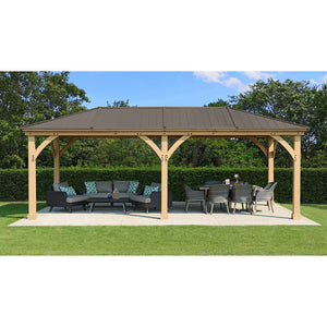 12 x 24 Meridian Gazebo - exterior grade cedar coated in natural cedar-color stain with coffee brown colored aluminum roof, 6” x 6” Posts with classic plinths, Heavy, curved corner gussets placed in a garden front view