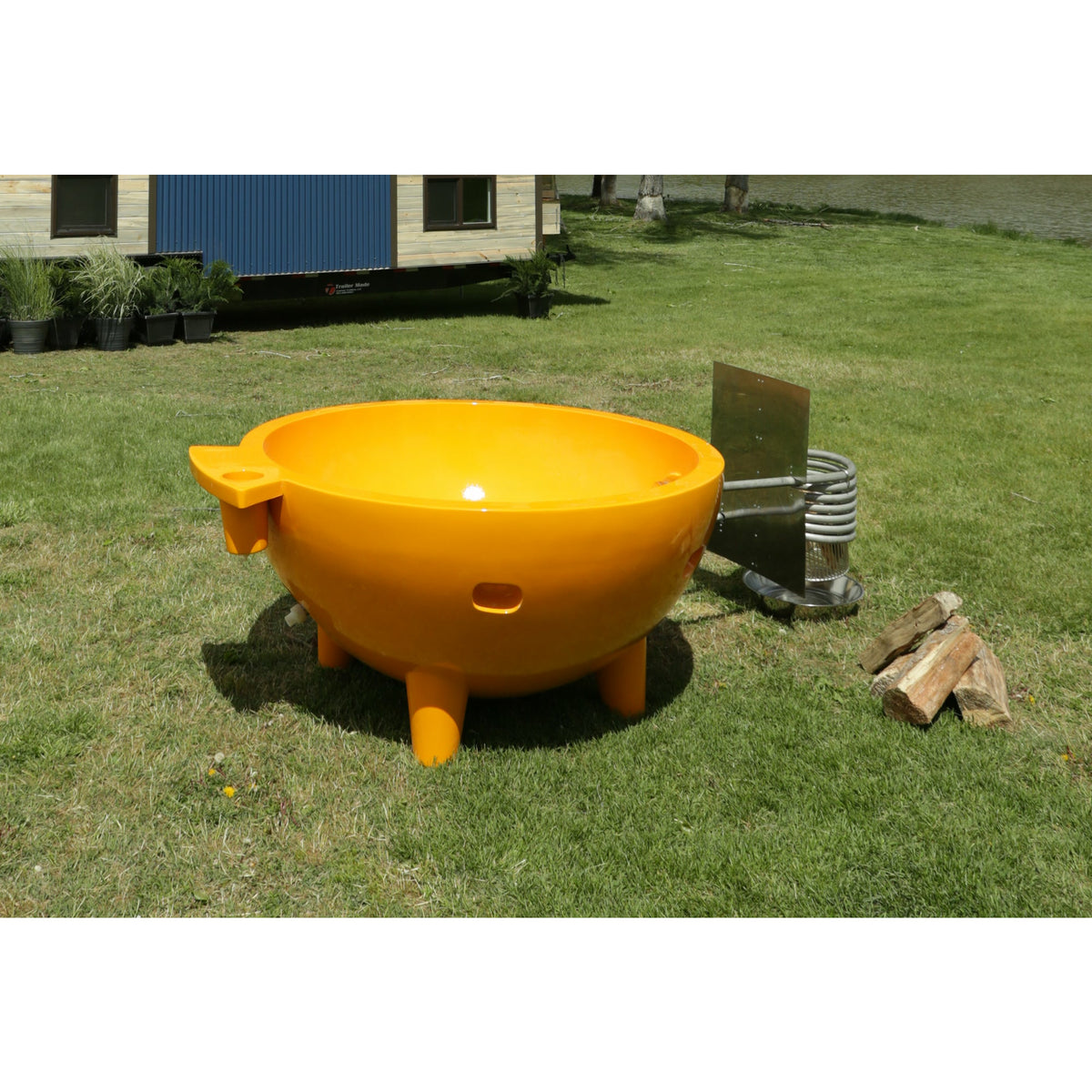 Orange ALFI FireHotTub The Round Fire Burning Portable Outdoor Hot Bath Tub made of acrylic and reinforced with a fiberglass core, Flat feet, stainless steel windscreen panels and ledge in the garden